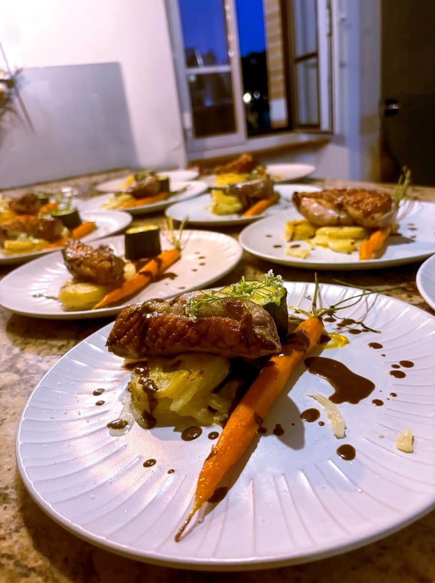 Assiette dressée avec une viande rôtie, une carotte et des pommes de terre, sur un plan de travail